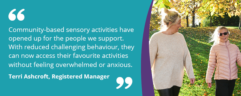 A picture of a person we support walking in the park with their support worker. Accompanying text reads, "Community-based sensory activities have opened up for the people we support. With reduced challenging behaviour, they can now access their favourite activities without feeling overwhelmed or anxious. Terri Ashcroft, Registered Manager."